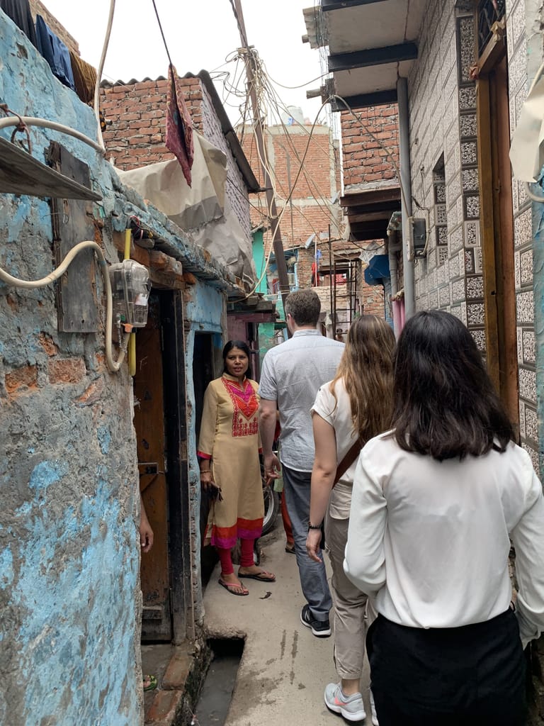 Skills-based volunteers from Tableau follow Operation ASHA staff into a crowded part of Tekhand Village in India