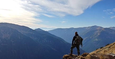man-on-mountain-looking-out-at-the-view-min