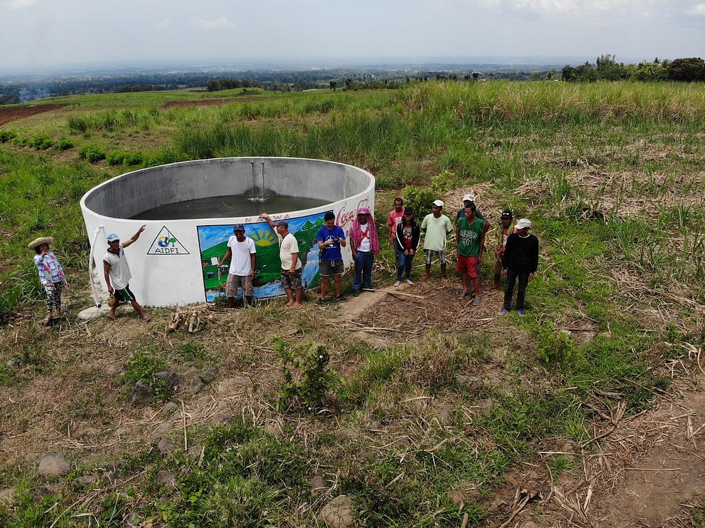 AIDFI team stands beside newly installed reservoir for Ram Pump to deliver water to village of Upper Atok