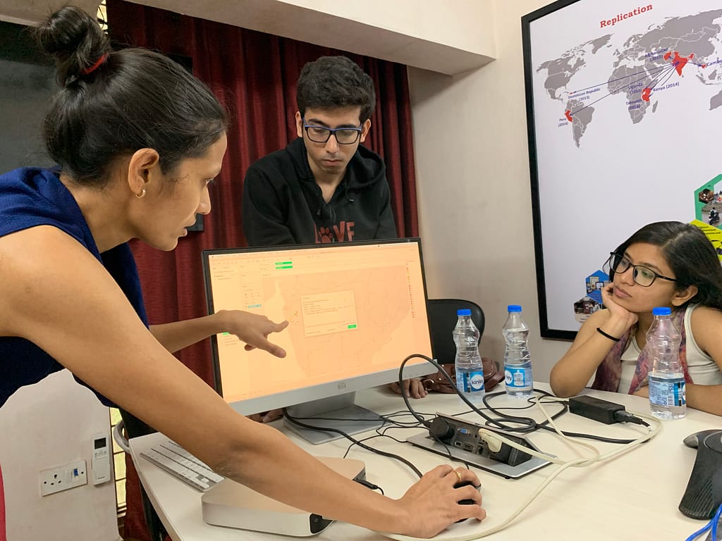 Operation ASHA staff pointing at a computer screen showing data clusters related to tracking TB in India