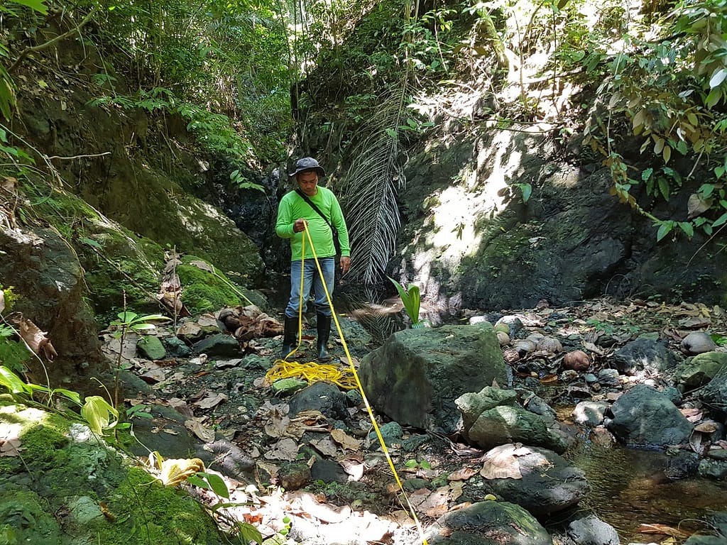 AIDFI team measuring the distance from the water source to the reservoir for Ram Pump installation