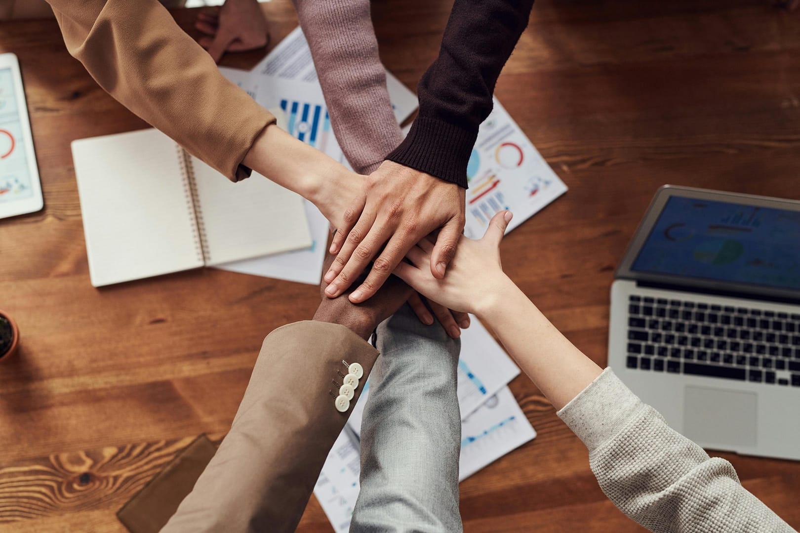 hands in a circle over a table representing collaboration