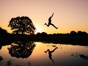 person leaping over a lake representing taking action